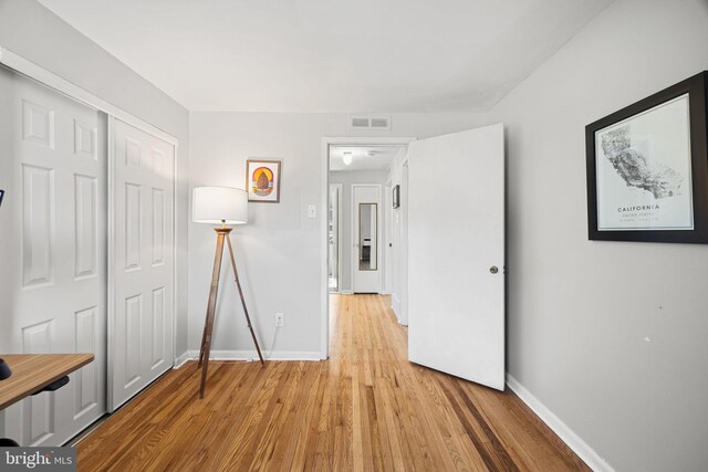 interior space with baseboards, light wood-type flooring, and visible vents