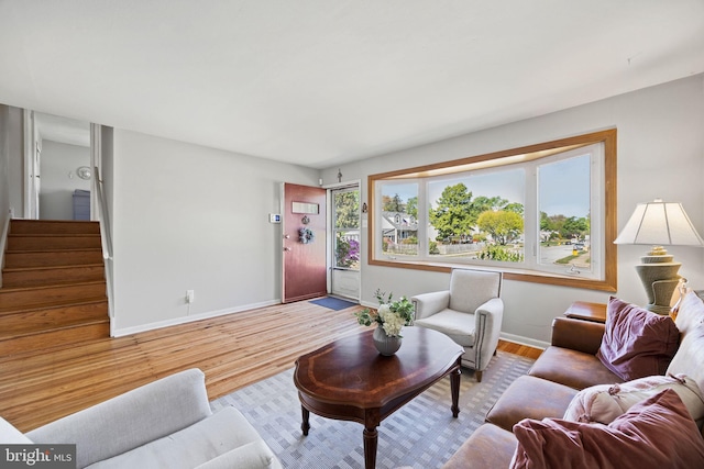 living room with baseboards, wood finished floors, and stairway