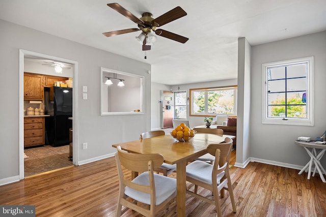 dining space with light wood-style floors, a ceiling fan, and baseboards
