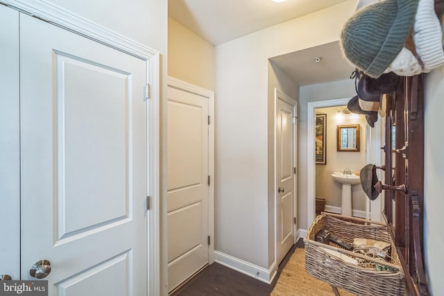 corridor featuring baseboards and a sink
