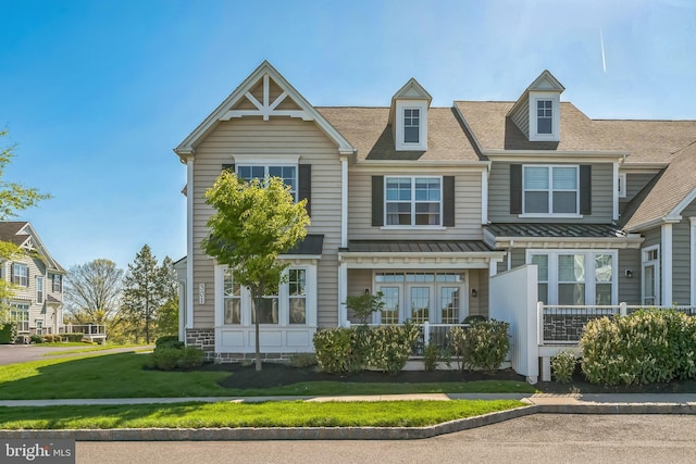 view of front of home with a shingled roof, metal roof, a front yard, and a standing seam roof