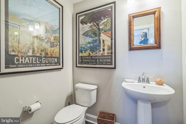 half bath featuring toilet and baseboards