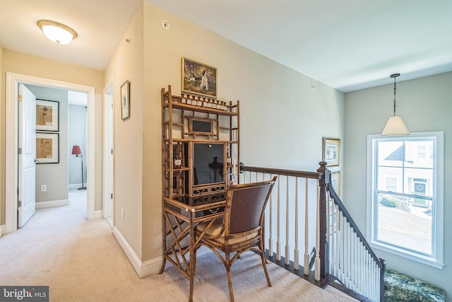 hallway featuring baseboards, light carpet, and an upstairs landing