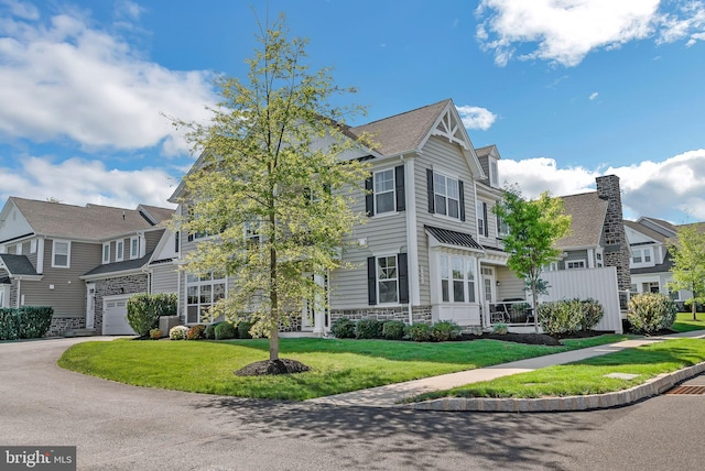 view of front of house with a garage, a residential view, a front yard, and stone siding