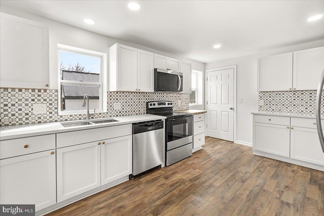 kitchen featuring white cabinets, a sink, dark wood finished floors, backsplash, and stainless steel appliances