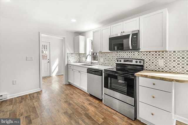 kitchen with butcher block counters, a sink, dark wood finished floors, backsplash, and stainless steel appliances