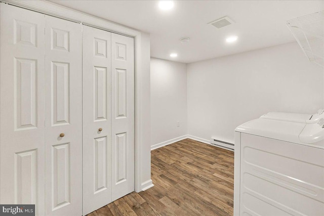 below grade area featuring wood finished floors, baseboards, a baseboard heating unit, recessed lighting, and washer and clothes dryer