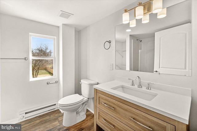 bathroom featuring visible vents, vanity, toilet, wood finished floors, and a baseboard heating unit