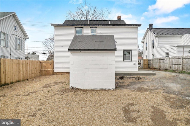 rear view of house featuring a chimney and a fenced backyard