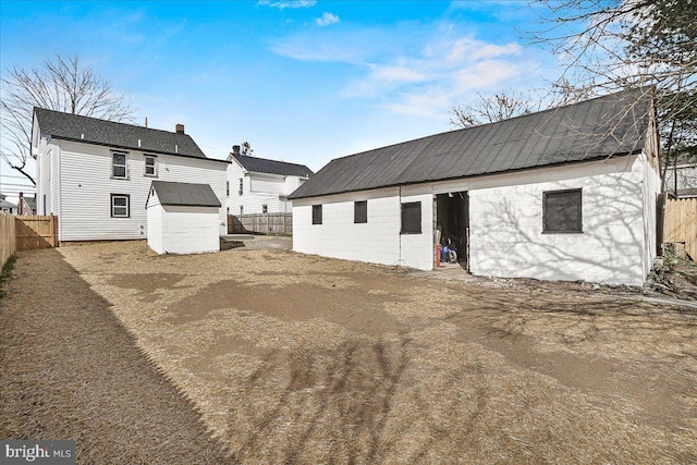 rear view of property featuring a fenced backyard, an outbuilding, metal roof, and a shed