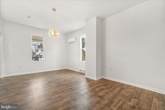 spare room featuring an AC wall unit, dark wood finished floors, a wealth of natural light, and a baseboard radiator