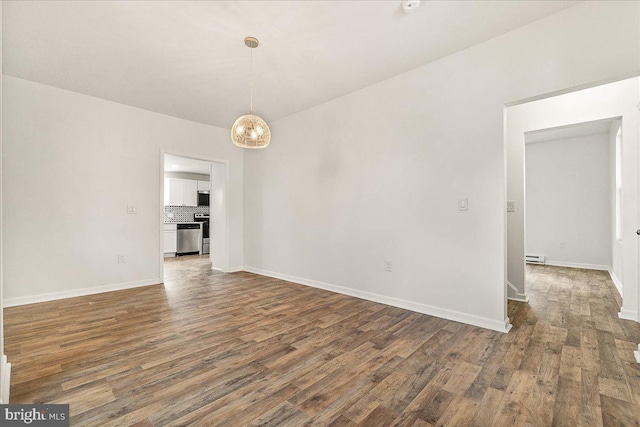 spare room featuring baseboards, a baseboard heating unit, and wood finished floors