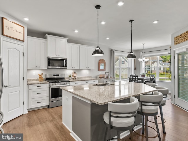 20515 Anchor Ln, Frankford, DE 19945 - kitchen featuring white cabinets, appliances with stainless steel finishes, a sink, light wood finished floors, and a kitchen island with sink