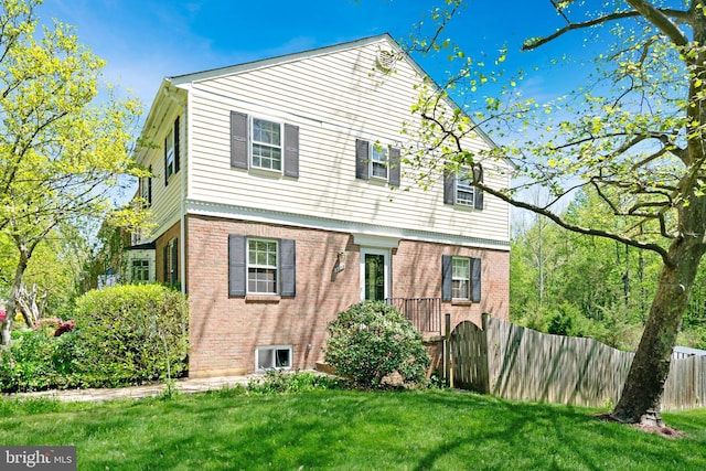 view of front of property featuring brick siding, fence, and a front yard