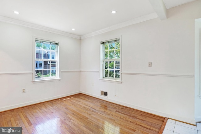 empty room with baseboards, a wealth of natural light, wood-type flooring, and visible vents