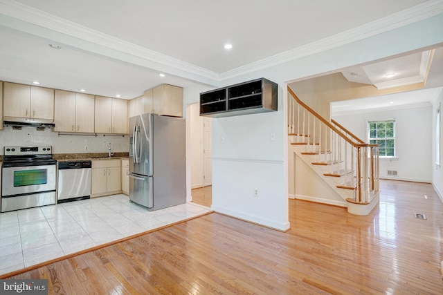 kitchen with light wood-type flooring, under cabinet range hood, tasteful backsplash, a sink, and stainless steel appliances