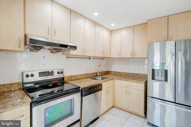kitchen with decorative backsplash, a sink, light stone counters, under cabinet range hood, and stainless steel appliances