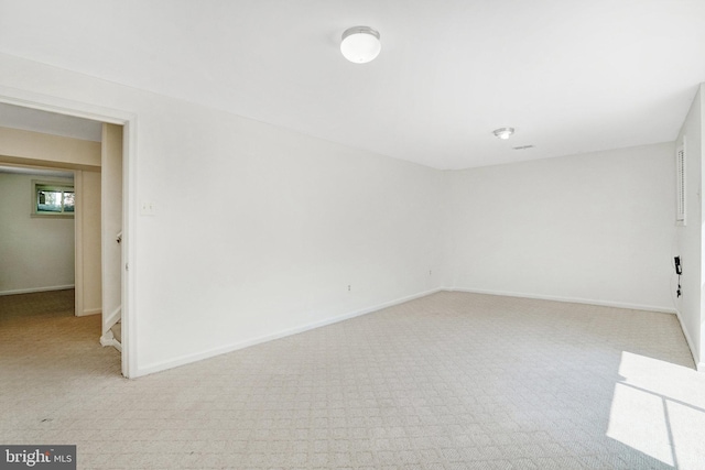 spare room with light colored carpet and baseboards