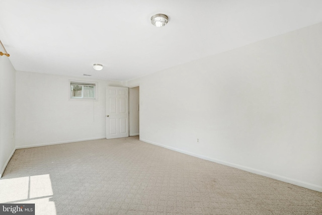 spare room with baseboards and light carpet