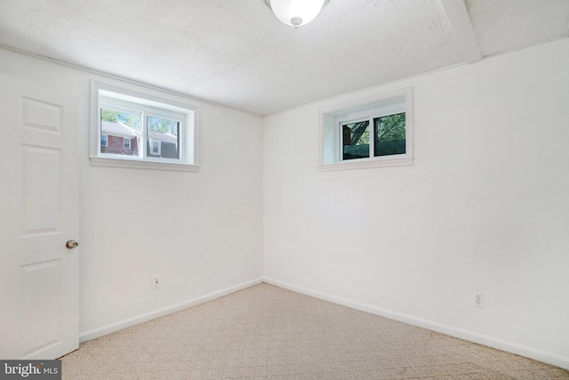 below grade area with carpet flooring, a textured ceiling, and baseboards