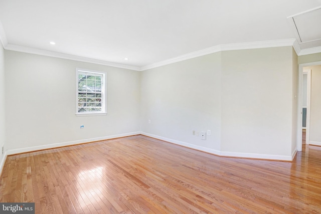 spare room with crown molding, light wood-style flooring, attic access, recessed lighting, and baseboards