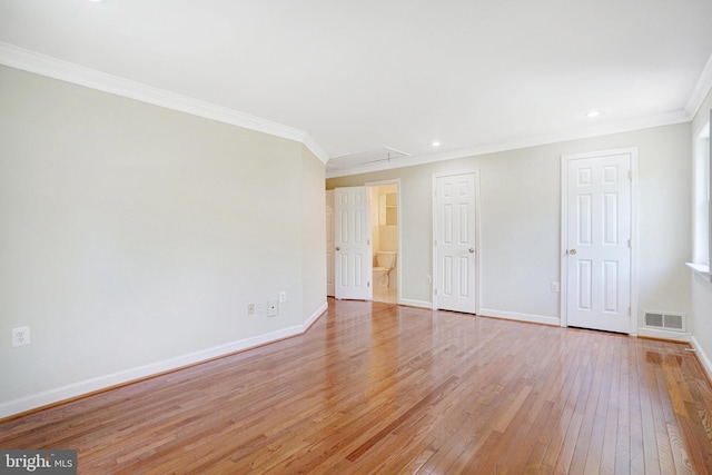 unfurnished room featuring crown molding, attic access, baseboards, light wood-type flooring, and visible vents