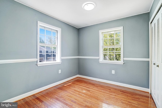 unfurnished bedroom with baseboards, wood finished floors, and a closet