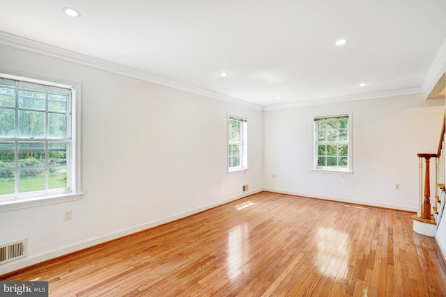spare room with light wood-style floors, baseboards, crown molding, and visible vents