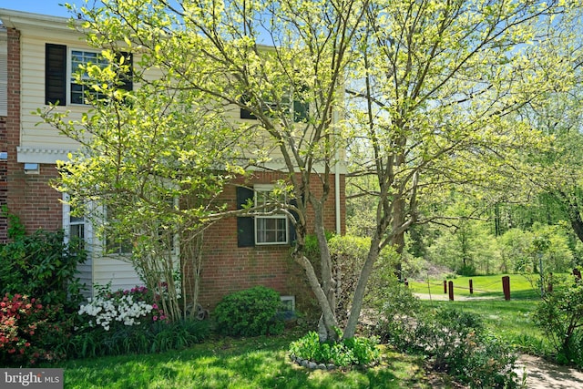 view of side of property featuring brick siding and a lawn