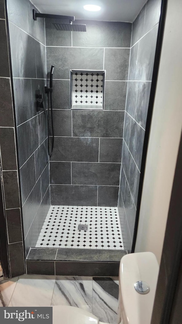 bathroom with toilet and a tile shower