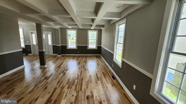 unfurnished living room featuring plenty of natural light, beamed ceiling, coffered ceiling, and wood finished floors