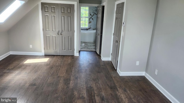 bonus room featuring a skylight, baseboards, and dark wood-type flooring