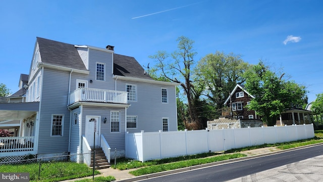 exterior space with fence private yard, a chimney, a balcony, and entry steps