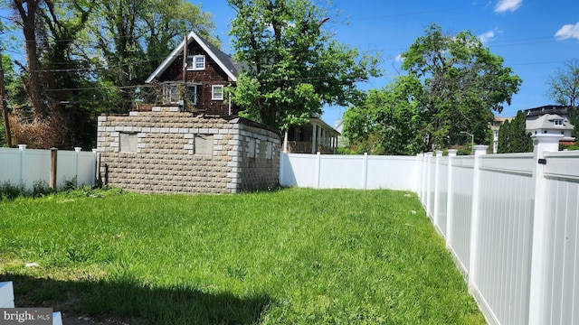 view of yard with a fenced backyard, an outbuilding, and a storage shed