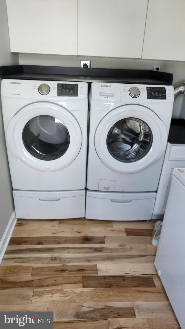 clothes washing area featuring washer and clothes dryer and wood finished floors