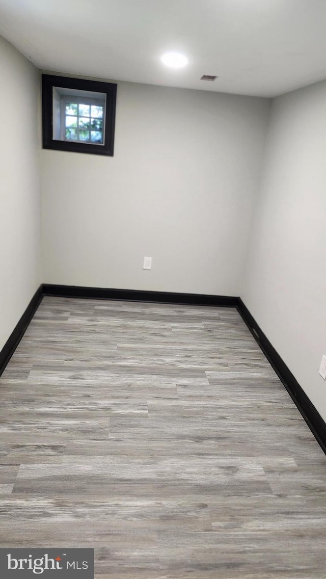 unfurnished room with baseboards, wood finished floors, and visible vents
