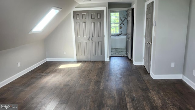bonus room with dark wood-type flooring, baseboards, and lofted ceiling with skylight