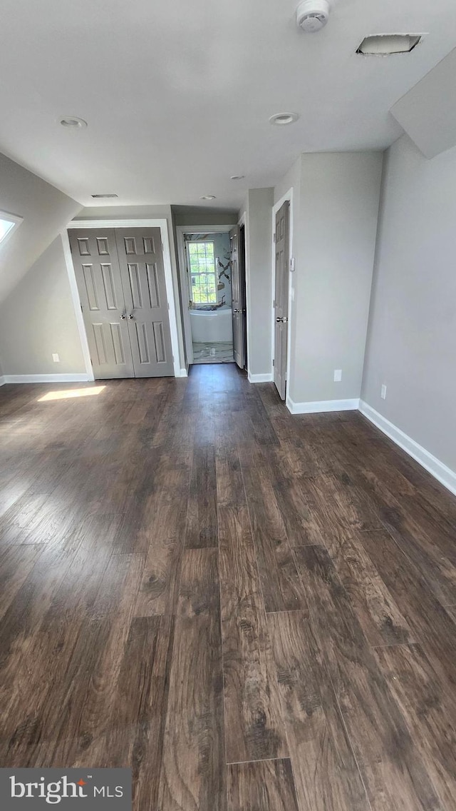 unfurnished living room featuring baseboards and dark wood-style flooring