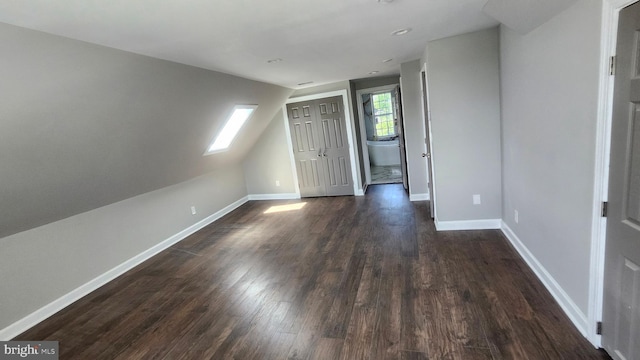 interior space featuring baseboards, dark wood-style flooring, and lofted ceiling with skylight