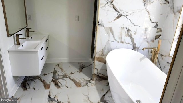 bathroom featuring double vanity, a freestanding tub, a sink, baseboards, and marble finish floor