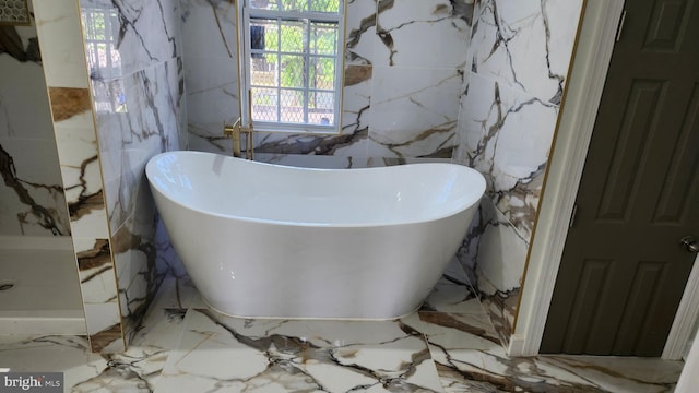 bathroom with a freestanding tub, marble finish floor, and a wealth of natural light