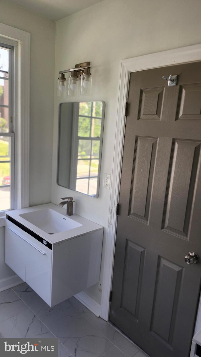 bathroom featuring a healthy amount of sunlight, marble finish floor, and vanity