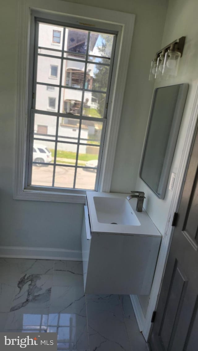 bathroom with baseboards, vanity, and marble finish floor