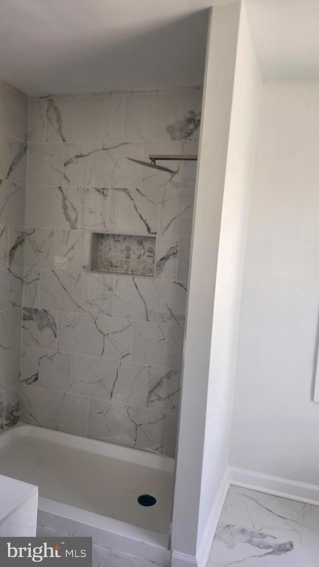 full bathroom featuring baseboards, a shower, and marble finish floor