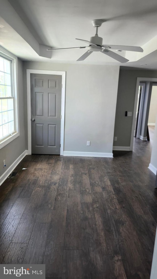 unfurnished bedroom with baseboards, a ceiling fan, and dark wood-style flooring