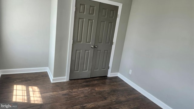 spare room featuring dark wood-style flooring and baseboards