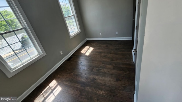 empty room featuring dark wood-style flooring and baseboards