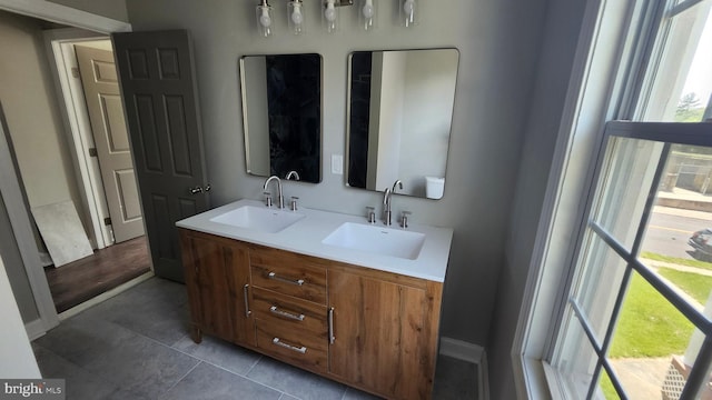 bathroom featuring double vanity, baseboards, a sink, and tile patterned flooring