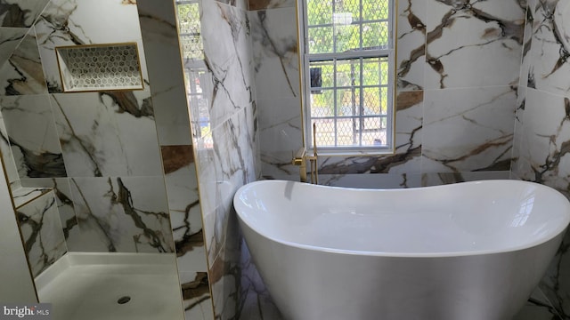full bathroom with a freestanding tub and tile walls