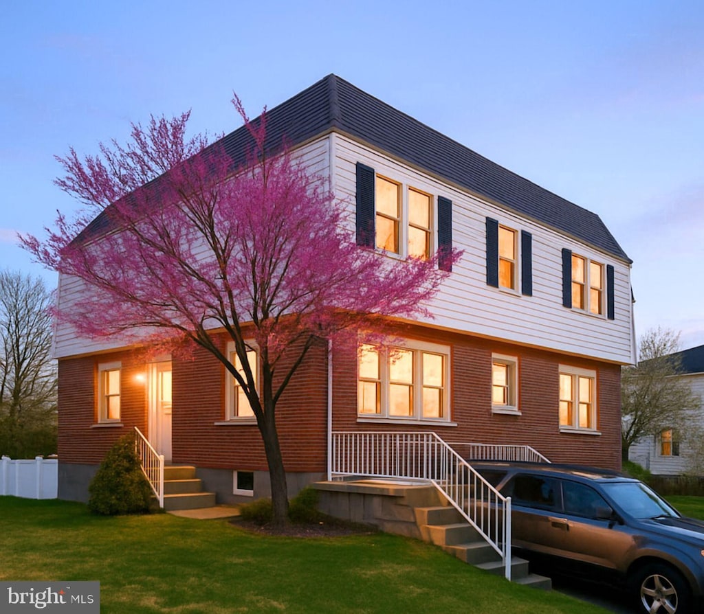view of front of home with brick siding, fence, and a front yard